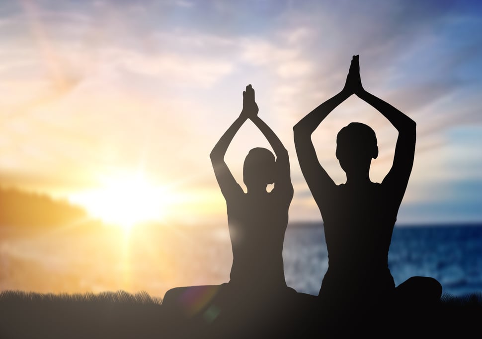 Couple Doing Yoga in Lotus Pose over Sunset